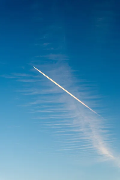 L'avion vole bas dans le ciel, laissant une traînée blanche — Photo