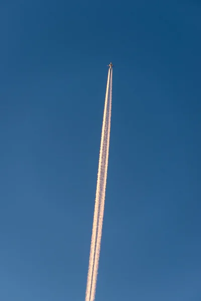 O avião voa baixo no céu, deixando um rastro branco — Fotografia de Stock