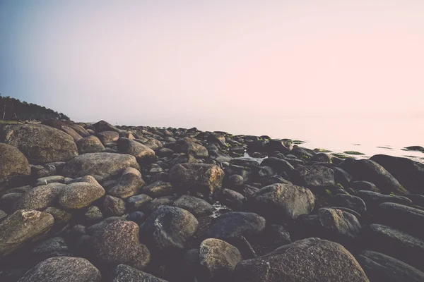 Каменистый пляж на закате с молочной водой - ретро, винтажный — стоковое фото