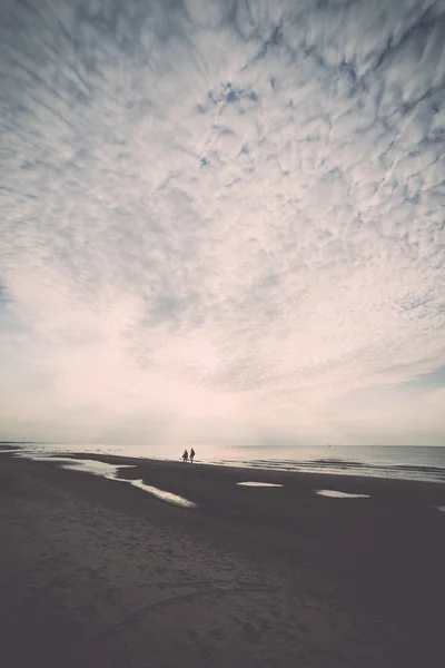 Az emberek séta a homokos tengerparton naplemente - retro, vintage — Stock Fotó