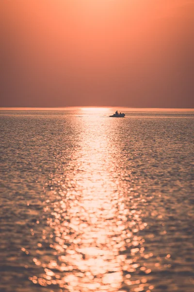 Bateau au coucher du soleil dans la mer avec des reflets et des nuages - retr — Photo