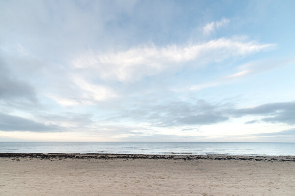 baltic beach in fall with clouds and waves towards deserted dune