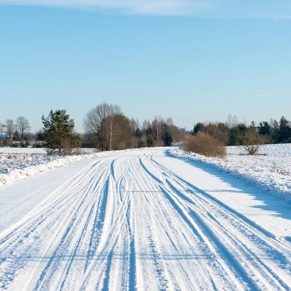 Nevado camino de invierno con marcas de neumáticos — Foto de Stock