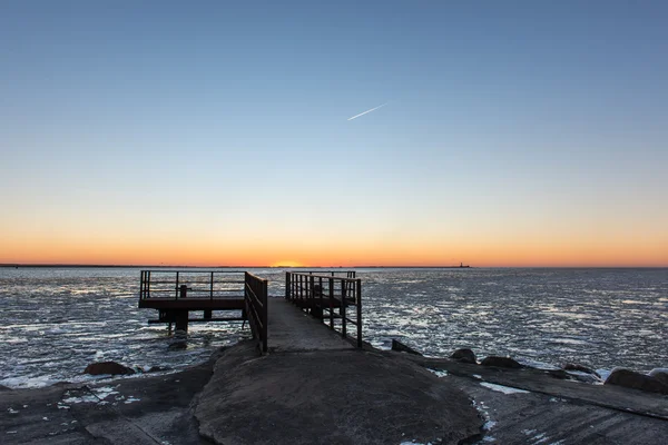 Zonsondergang over bevroren zee met oude metalen brug — Stockfoto