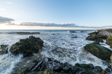Dalgalar kayaların üzerinden'nde Günbatımı kırma
