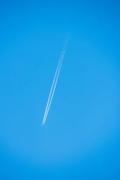 O avião voa baixo no céu, deixando um rastro branco — Fotografia de Stock