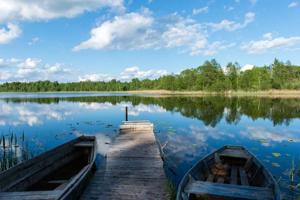 青い湖ボートとボードの上の青い空に白い雲 — ストック写真