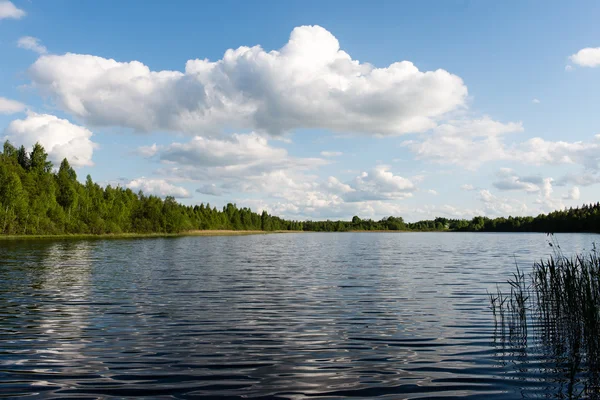 White clouds on the blue sky over blue lake — Stock Photo, Image