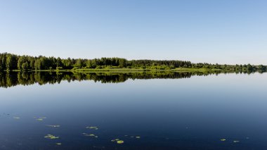 Sakin göl kenarında simetrik yansımalar