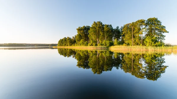 Symmetric reflections on calm lake — Stock Photo, Image