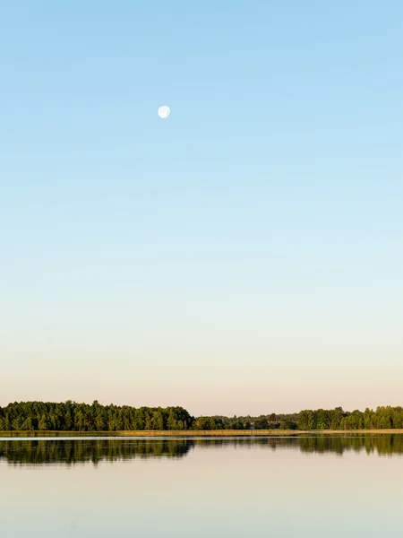 Sakin göl kenarında simetrik yansımalar — Stok fotoğraf