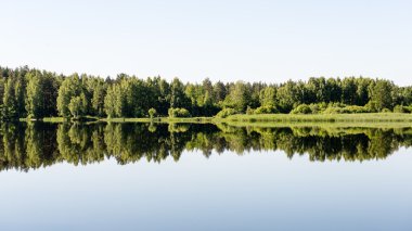 Sakin göl kenarında simetrik yansımalar