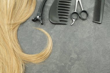 Sarı bukleli saç ve kuaför seti gri arka planda izole edilmiş. Makas ve tarak. Mesajın için yer aç. Güzellik konsepti. 
