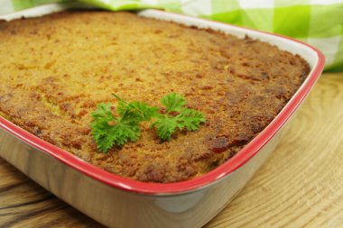 Patates kugel. Tahta servis tahtasındaki beyaz bir tavada fırında patates pudingi..