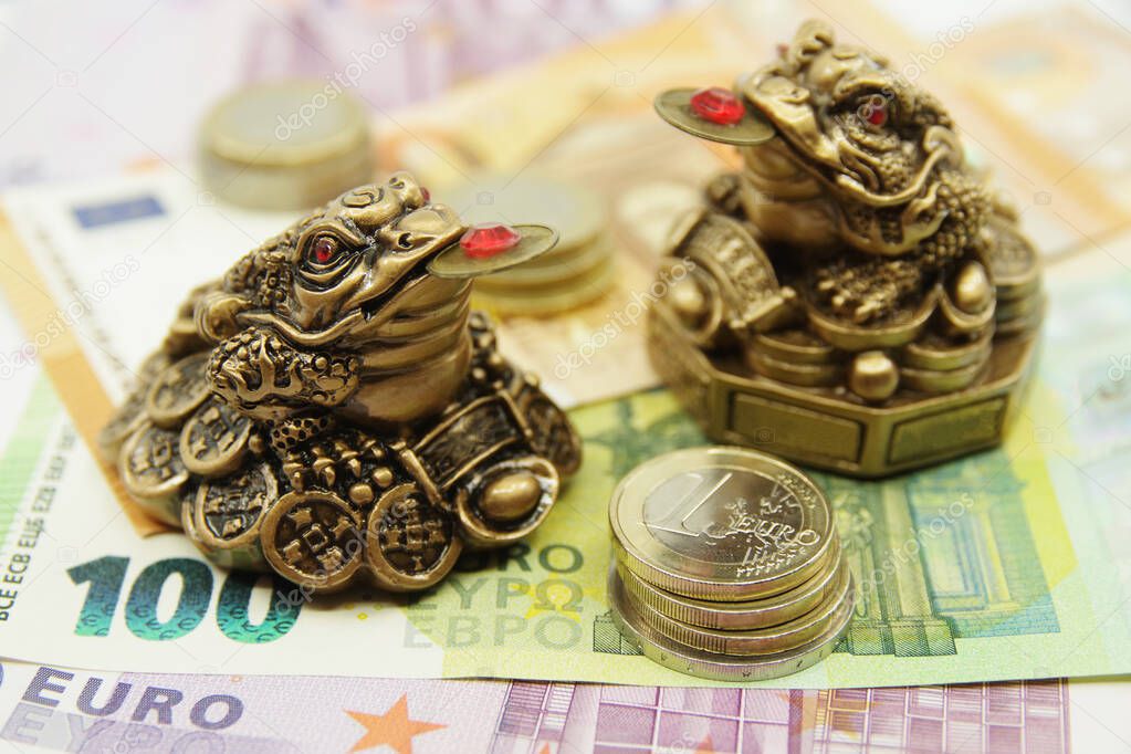 Two Chinese Feng shui frogs sitting on euro banknotes. Symbol of abundance and luck. 