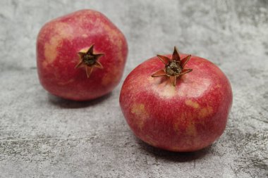 Gri arka planda olgun kırmızı nar meyveleri. Mevsimlik meyveler. Kraliyet meyvesi. Seçici odak.