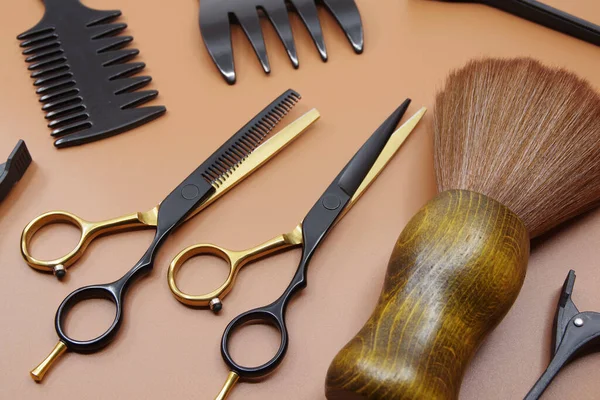 Professional hairdressers tools isolated on brown background. Hairdressers scissor, comb and hairpins.