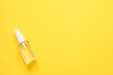 Sarı arka planda şeffaf plastik şişede alkol spreyinin üst görüntüsü, Coronavirus koruma ekipmanları arka plan kavramı.