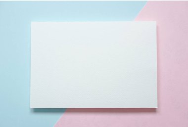 Boş a4 kağıt broşürünün üst görünümü açık mavi ve pembe pastel arkaplan üzerine kart oluşturur.