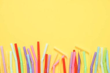 Sarı zemin üzerinde renkli plastik pipetlerin üst görünümü, düz yatay, kopyalama alanı.