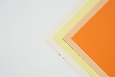 Geometrik desenli renkli kağıtların istiflenmesi ile soyut arka plan kavramı, boş turuncu kağıt katmanları ve bej rengi, sarı, beyaz arkaplanda krem rengi kağıt.