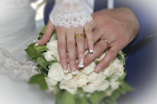 Mãos e anéis no buquê de casamento — Fotografia de Stock