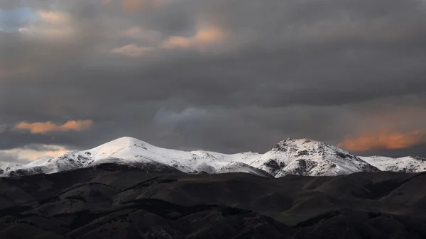 Nuvens sobre as montanhas nevadas ao pôr do sol — Fotografia de Stock