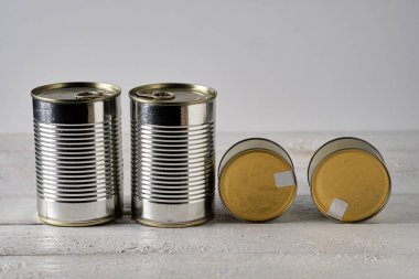 Beyaz ahşap masada dört teneke kutu.