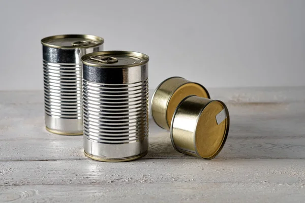 Beyaz ahşap masada dört teneke kutu.