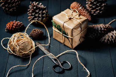 Kraft kağıdına sarılı hediye kutusu, halat makası ve siyah kırsal ahşap üzerinde ananas.