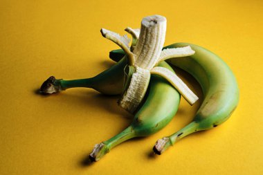 Yeşil muzlar, sarı arka planda derisi olmayan.