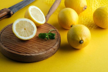 İkiye bölünmüş limon ve sarı arka planda taze limonlar.