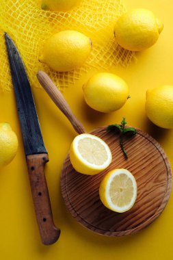 Yukarıdan ikiye bölünmüş limon manzarası, kırsal bıçak ve sarı arka planda taze limon.