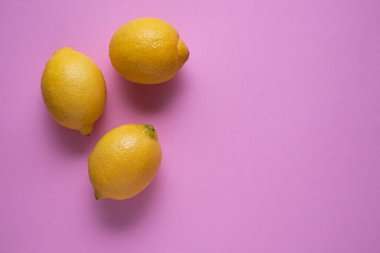 Pembe arka planı ve kopyalama alanı olan üç taze limon