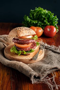 Köy ahşap tabanlı domatesli duble burger ve marul.