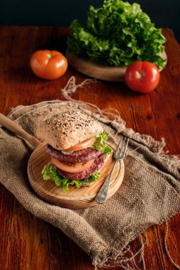 Köy ahşap tabanlı domatesli duble burger ve marul.