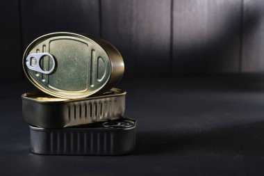 Siyah arkaplan üzerine istiflenmiş teneke kutuların yakın plan görüntüsü ve kopyalama alanı