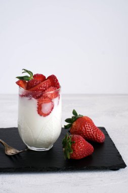 Sütlü tatlı. Bardakta taze çilekli yoğurt.
