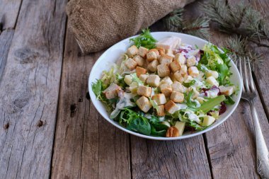 Taze sebzelerden yapılmış sağlıklı Sezar salatası ve köy tahtasında tavuk.