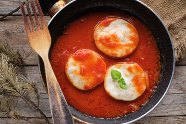 Kırsal ahşap masada, tavada domatesli madalyonlar.