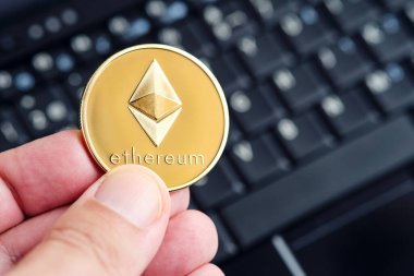 Ethereum kripto para birimi arka planda bir bilgisayar klavyesi ile bir elde tutulur