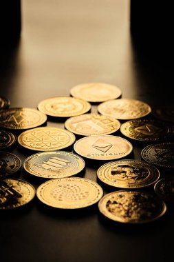Birkaç kripto para birimi bir masanın üzerine yerleştiriliyor. Her sikkenin kendine has bir tasarımı var. Sikkeler ışığı yansıtıyor ve Ethereum 'u vurgulayarak farklı sembol ve logolar gösteriyor..