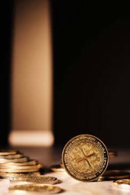 Parlak bir Xrp madeni para yığını üzerine belirgin bir şekilde yerleştirilmiştir. Arka plan karanlık, düşük ışıkta paranın detaylarına odaklanmamızı sağlıyor..