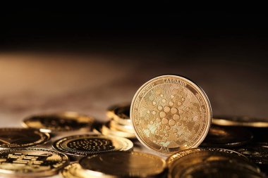 Cardano 'nun önemli rol oynadığı bir kripto para koleksiyonu sergilenmektedir. Paralardan yansıyan ışık, detaylı yüzeylerini vurguluyor..