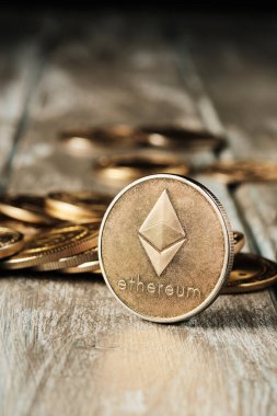 Üzerinde bir sembol bulunan kripto para, etrafına saçılmış altın paralarla çevrili ahşap bir yüzeye yerleştirilir. Ayarlar basit ve odaklanmış görünüyor..