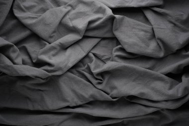 Katları ve kırışıklıkları olan gri kumaş manzarası. Doku görünür, materyalin karmaşık detaylarını gösteriyor. Kumaşın yüzeyinde ışık yanar.