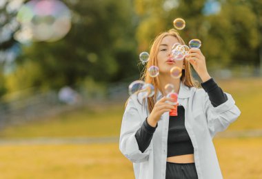 Çimlerin üzerinde duran ve kabarcıklar çıkaran güzel genç