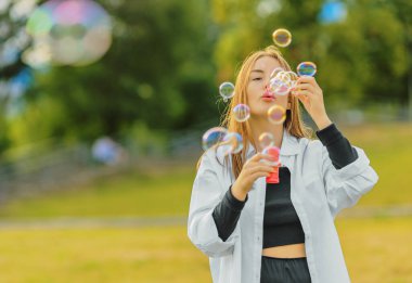 Çimlerin üzerinde duran ve kabarcıklar çıkaran güzel genç