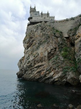 Gri taştan yapılmış eski bir şatonun arka planı, Kırım 'daki bir kayanın üzerinde. Deniz tarafından yıkanan kalenin kimliği..