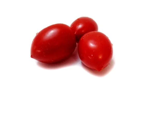 Beyaz arka planda, su damlacıklı üç kırmızı domates.. 